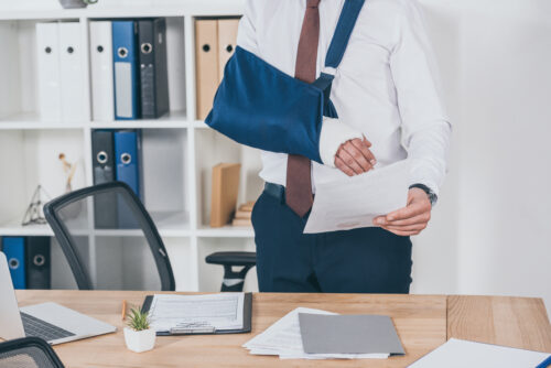 man with broken arm working at desk with paper in hand
